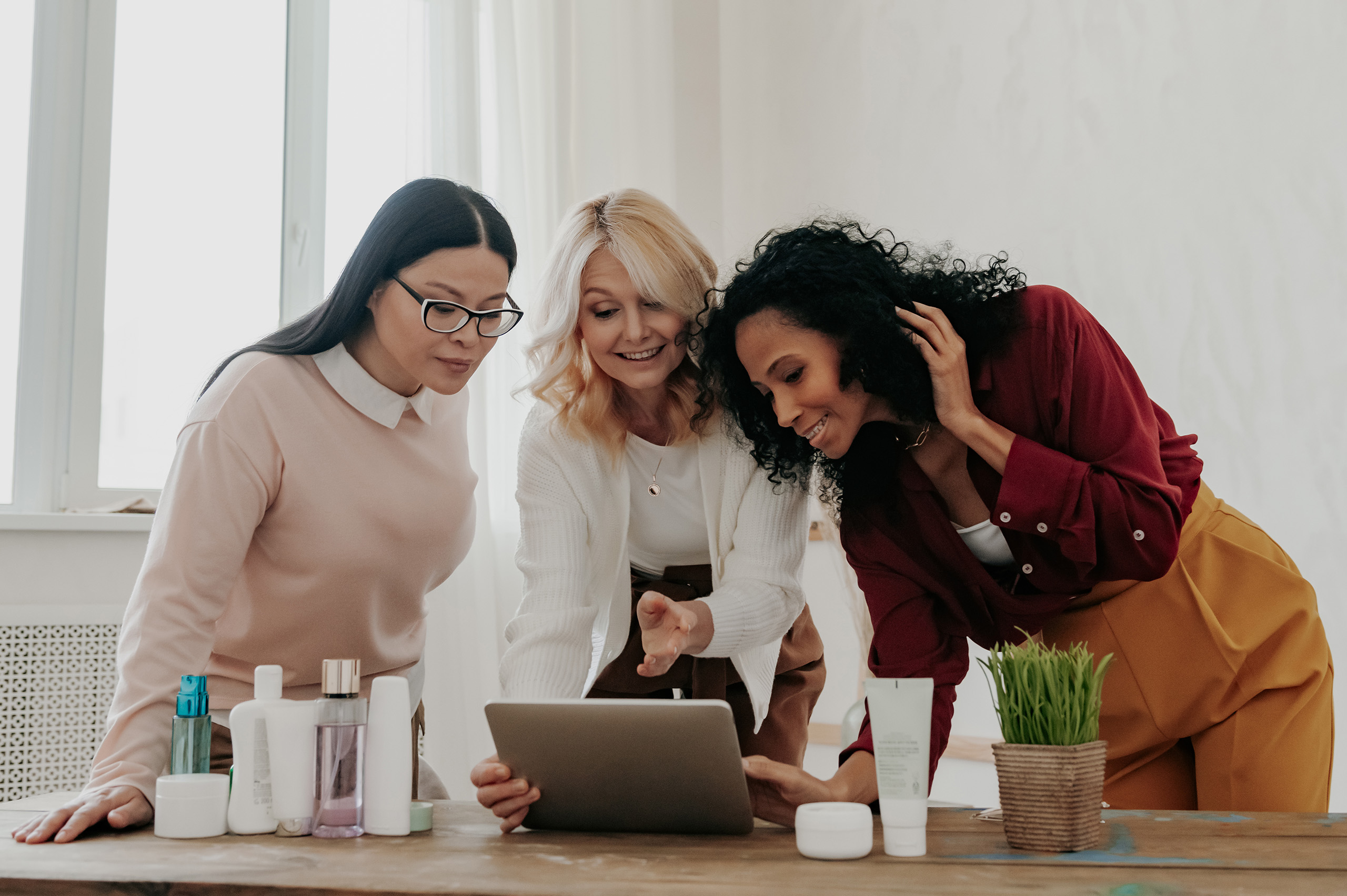 Three women buying beauty products online while spending time together